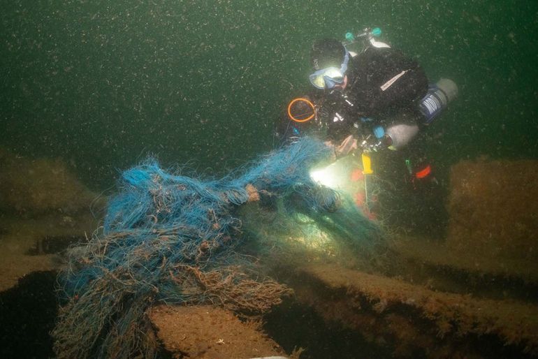 Duiker verwijdert resten vistuig (staand want) van een scheepswrak tijdens expeditie 25