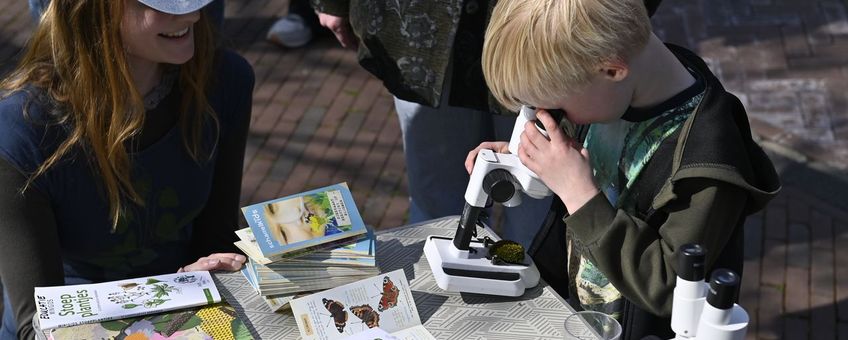 Jongen kijkt door microscoop tijdens Expeditie stadsnatuur