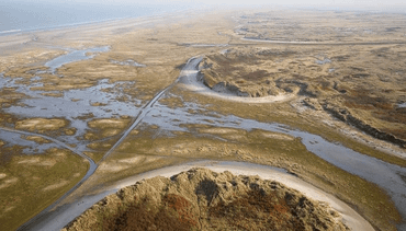 Zogenaamde 'washover' of overslaggrond bij paal 10 op Schiermonnikoog. Bij storm zet de zee zand en slib af achter de duinen.