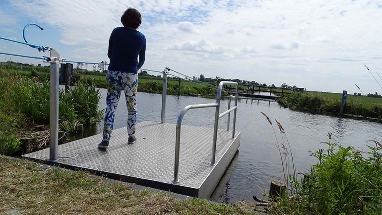 Wandelaar steekt met trekpontje Veldwetering over. Dit maakt deel uit van een nieuwe wandelverbinding dwars door weilanden in Galgenland, Wilnis, tussen de knooppunten 46 en 47 van het wandelnetwerk in het Groene Hart