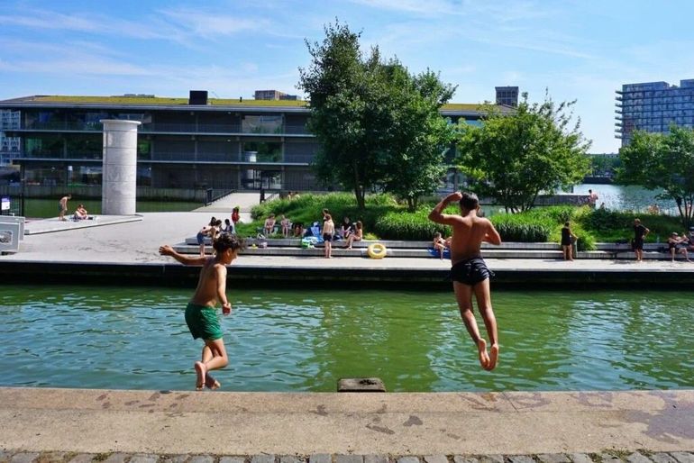 Jongens springen in het water vanaf de kade tegenover het ponton aan de Antoine Platekade 