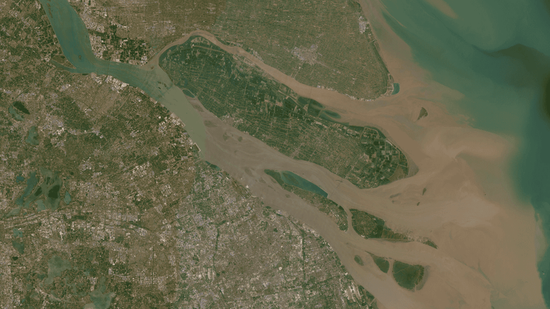 Satellietfoto van de Yangtze bij Shanghai (China), waar het troebele, bruine water de hoge sedimentaanvoer illustreert