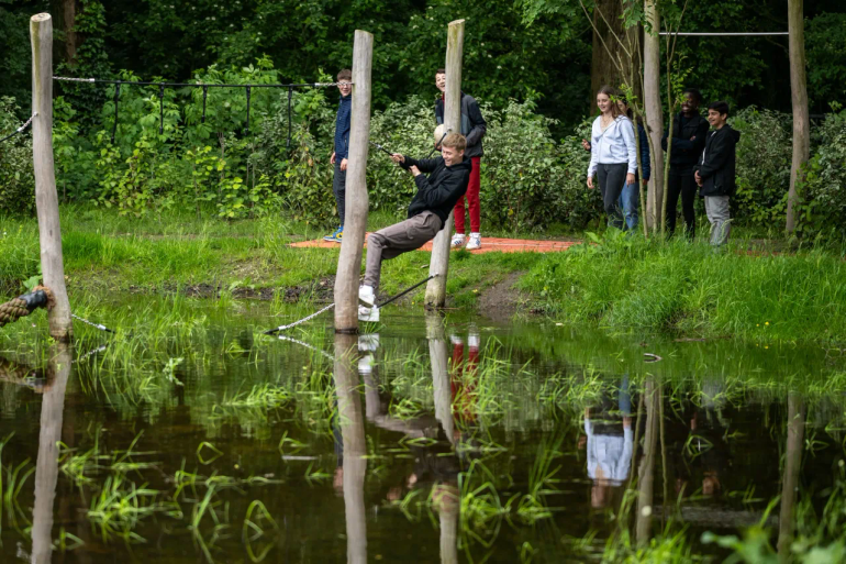 Jongeren op een hindernisbaan op het groene schoolplein van een middelbare school