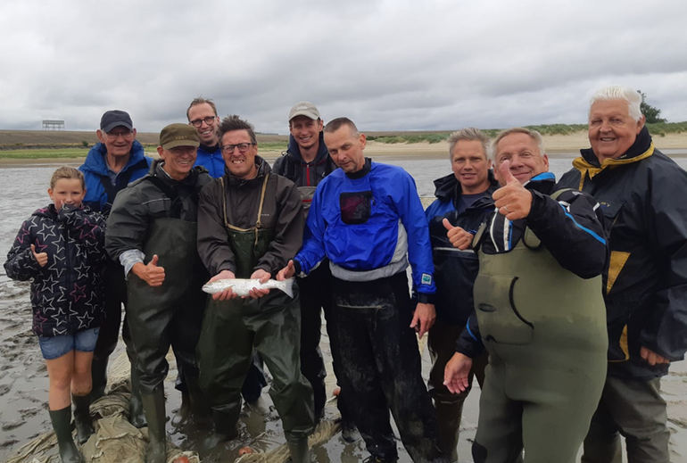 Vrijwilligers tonen een tijdens het zegenvissen in de Voordelta gevangen Atlantische forel (foto uit pre-coronatijdperk)