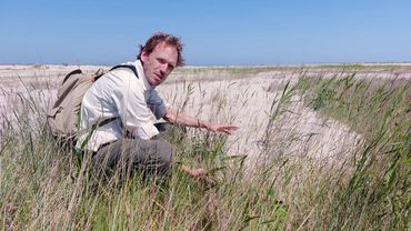 Boswachter Joeri Lamers schat de hoogte van de zandlaag in, die met wash-overs steeds verder het het land op komt