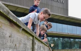 Schoolkinderen zoeken waterdiertjes bij het NIOO