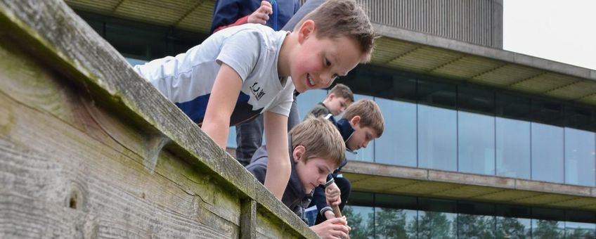 Schoolkinderen zoeken waterdiertjes bij het NIOO