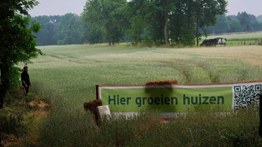Landschap met spandoek 'Hier groeien huizen'