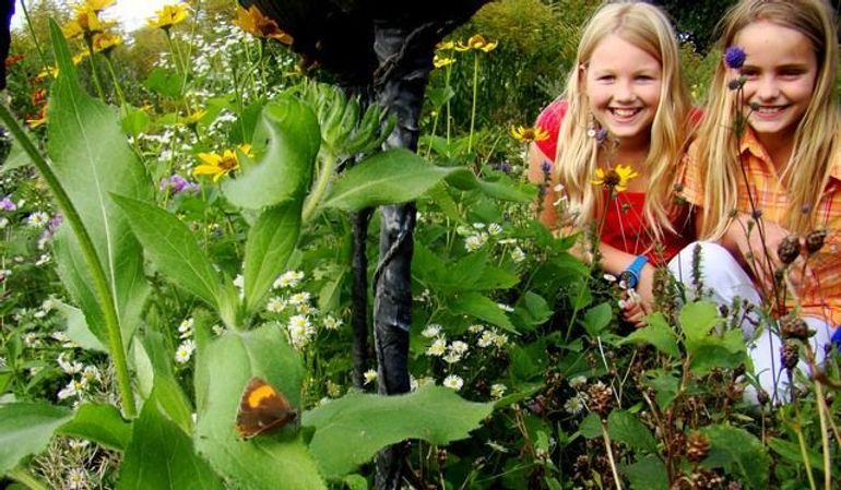 Meisjes zien een sleedoornpage in een vlindertuin