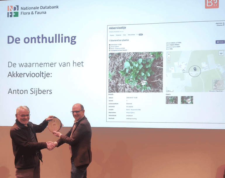 NDFF‑vertegenwoordiger Jan Willem van der Vegte overhandigt de erkenning van de 250 miljoenste waarneming in de NDFF aan Anton Sijbers uit Bakel, die de waarneming van het akkerviooltje deed