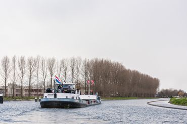 Eerste schip vaart door de bochtafsnijding Delftse Schie: de natuurvriendelijke oever in de nieuwe vaargeul is goed te zien