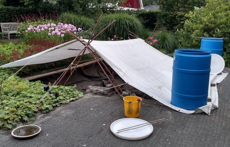 De vijver na de verwijderingsactie, met een afdak tegen inregenen van nieuw water en de opslagvaten op de hoekpunten.