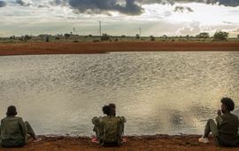 Drie vrouwen zitten bij een waterpoel in Kenia