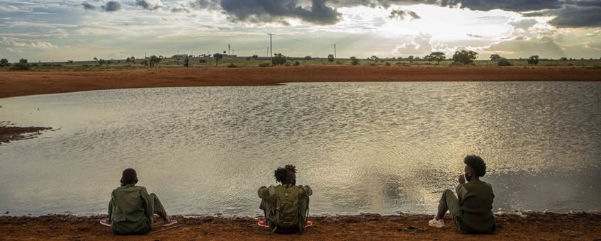 Drie vrouwen zitten bij een waterpoel in Kenia