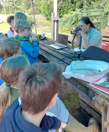 Een groep kinderen krijgt uitleg over het gebruik van een wildcamera