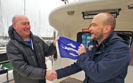 Schipper Sjef Mathijssen (links) ontvangt de eerste steurenvlag van Bram Houben van ARK Natuurontwikkeling