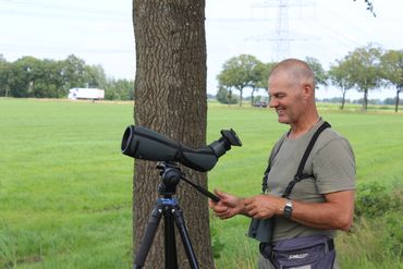 Jacques van der Ploeg speurt met zijn telescoop hoogspanningsmasten af op zoek naar boomvalken
