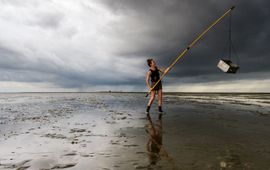 Jasper Doest Emma Penning sampling the mudflat for shrimp and crab, the skyline of Griend on the background.