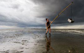 Emma Penning sampling the mudflat for shrimp and crab, the skyline of Griend on the background.