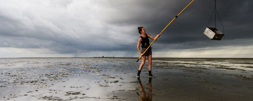 Emma Penning sampling the mudflat for shrimp and crab, the skyline of Griend on the background.