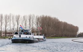 Eerste schip vaart door de bochtafsnijding Delftse Schie; de natuurvriendelijke over in de nieuwe vaargeul is goed te zien