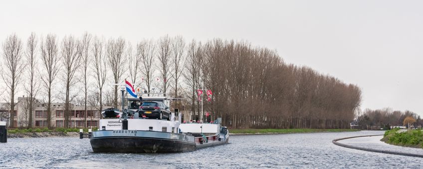 Eerste schip vaart door de bochtafsnijding Delftse Schie; de natuurvriendelijke over in de nieuwe vaargeul is goed te zien