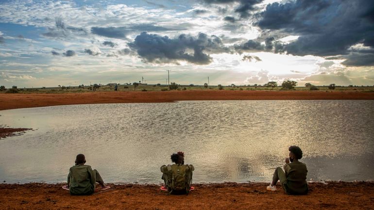 Drie vrouwen zitten bij een waterpoel in Kenia